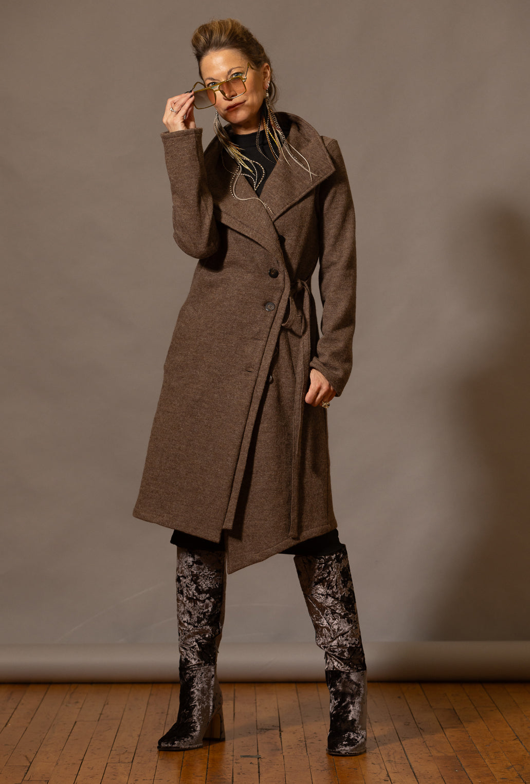 woman wearing a long merino sweater coat with asymmetrical hem button up with tie belt